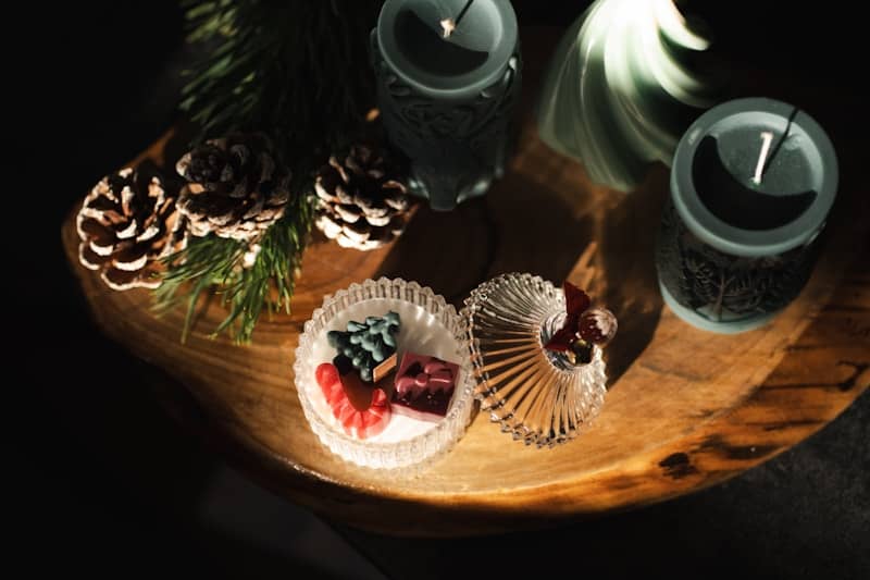 A wooden tray topped with pine cones and candles