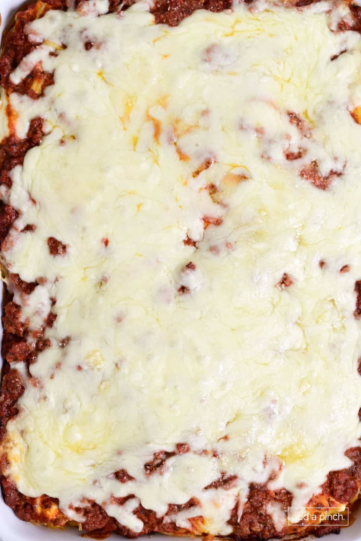 Million dollar spaghetti casserole in a baking dish topped with cheese.