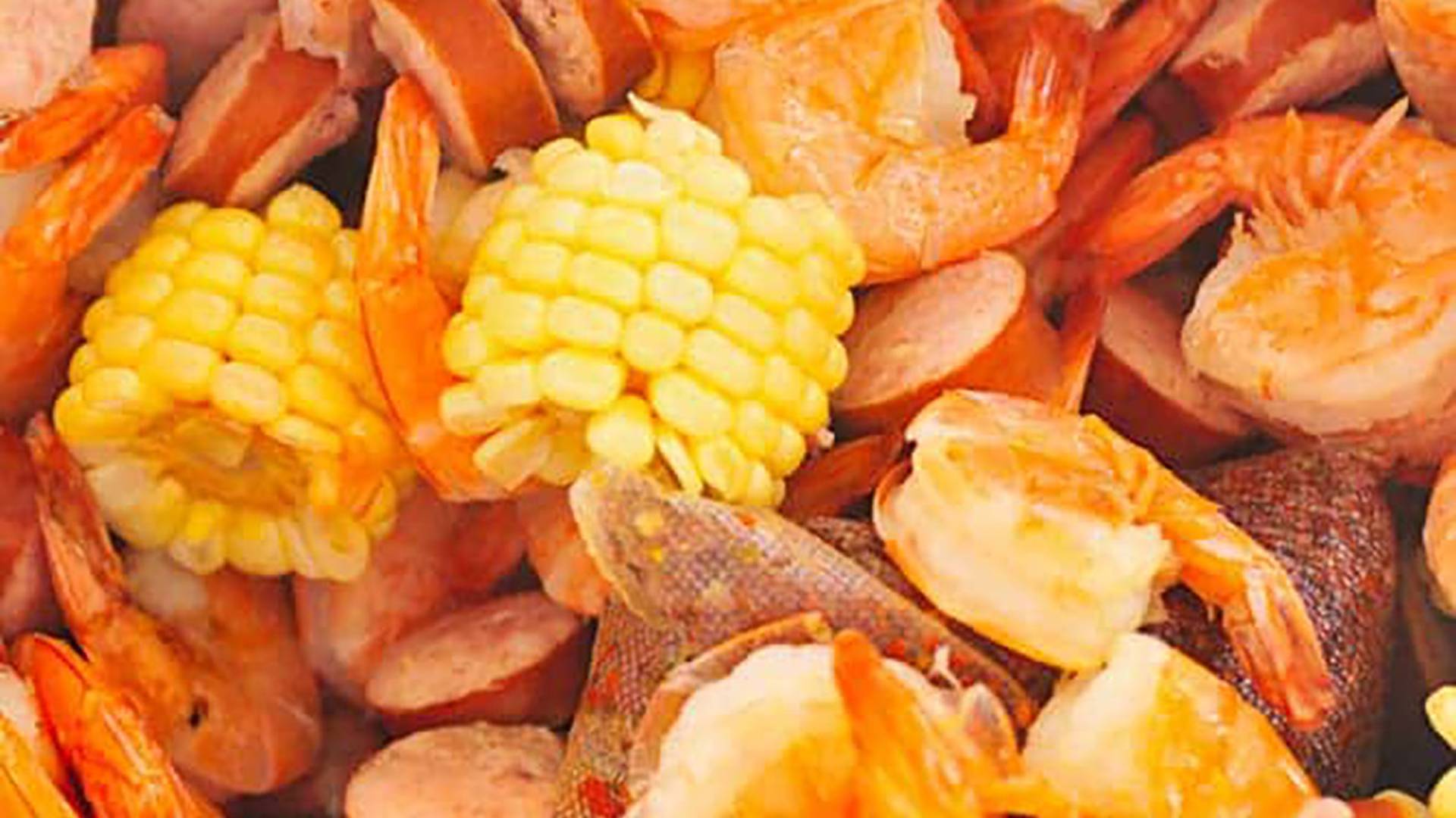 Shrimp boil in stockpot with shrimp, corn, sausage, and other ingredients.