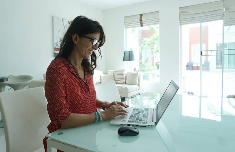 Woman is working on a laptop at a table.