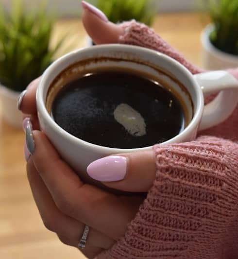 Hands holding a warm cup of black coffee