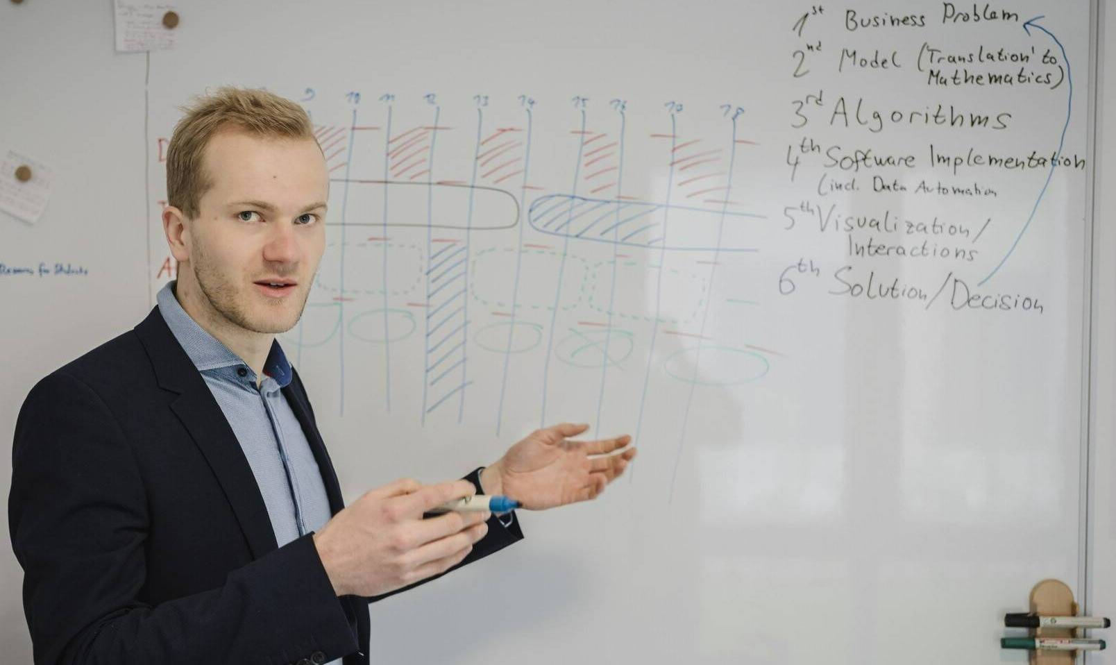 Tim Varelmann gestures in front of a whiteboard