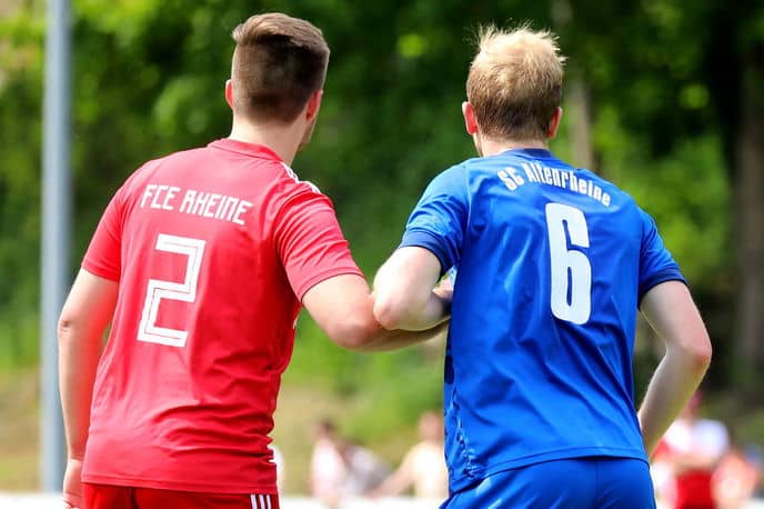 Two football players pushing each other at arms length