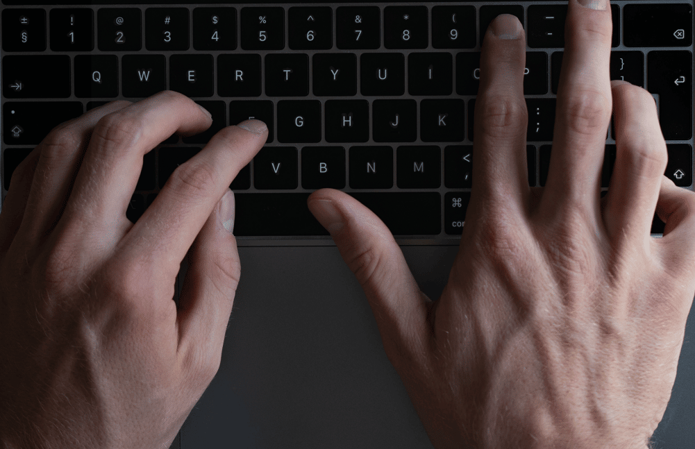 Two hands typing on a keyboard