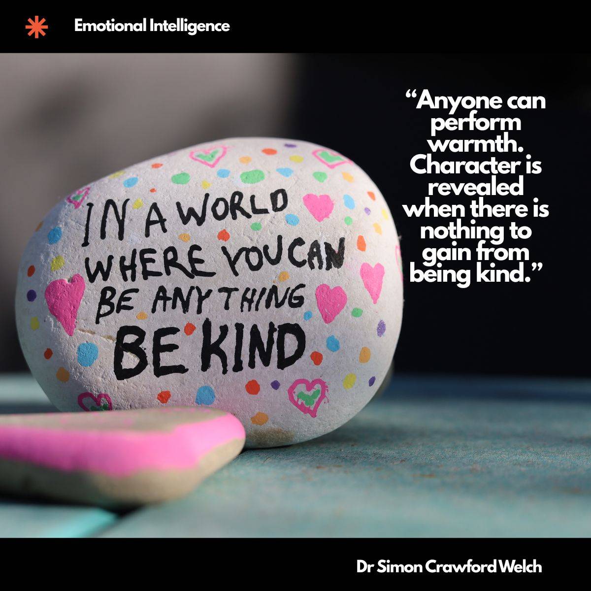 A smooth white stone painted with colorful dots and hearts rests on a teal surface, hand lettered with the words In a world where you can be anything be kind, with a pink painted stone in the foreground. The concept is quiet, unglamorous kindness offered without an audience. Text over the image reads: "Anyone can perform warmth. Character is revealed when there is nothing to gain from being kind." By Dr Simon Crawford Welch.