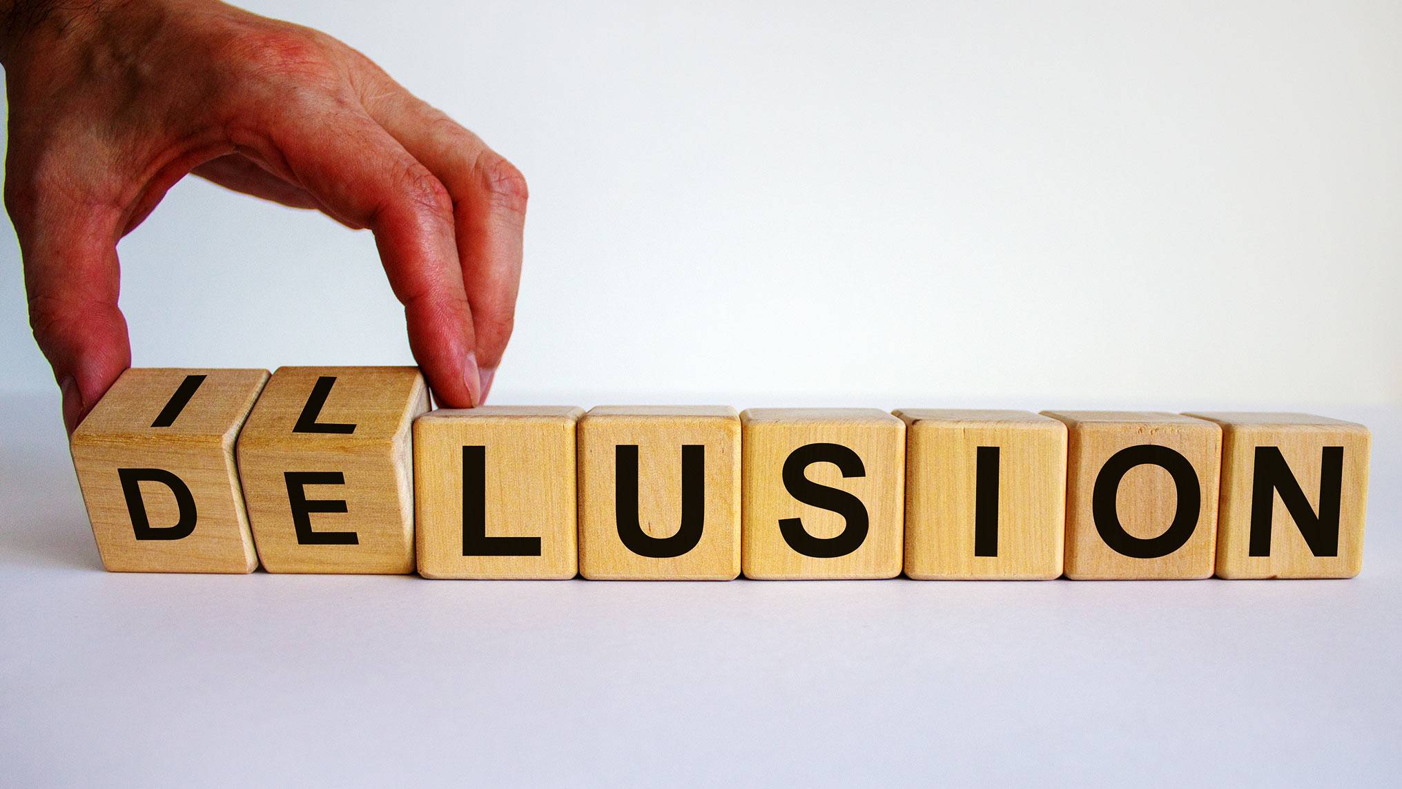 Letter blocks spelling out the words delusion and illusion, with two blocks switched to show the fine line between the two.