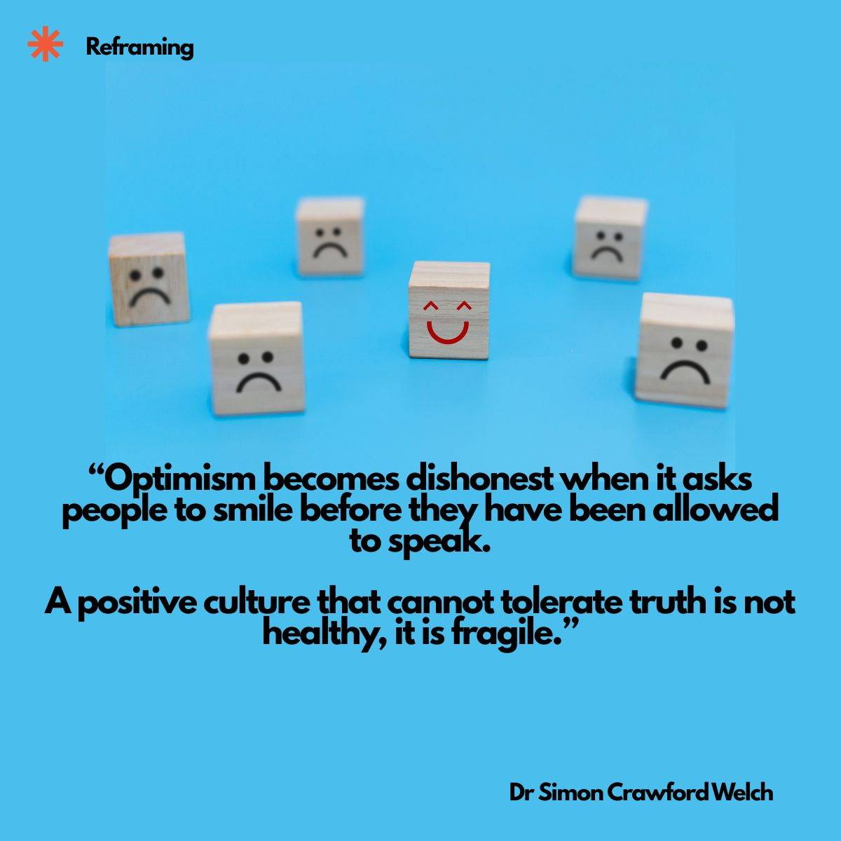 Visual description: Six small wooden blocks on a bright blue background. Five are drawn with black frowning faces and one in the center is drawn with a red smiling face. A small red asterisk and the label "Reframing" appear at the top. Concept: A single r