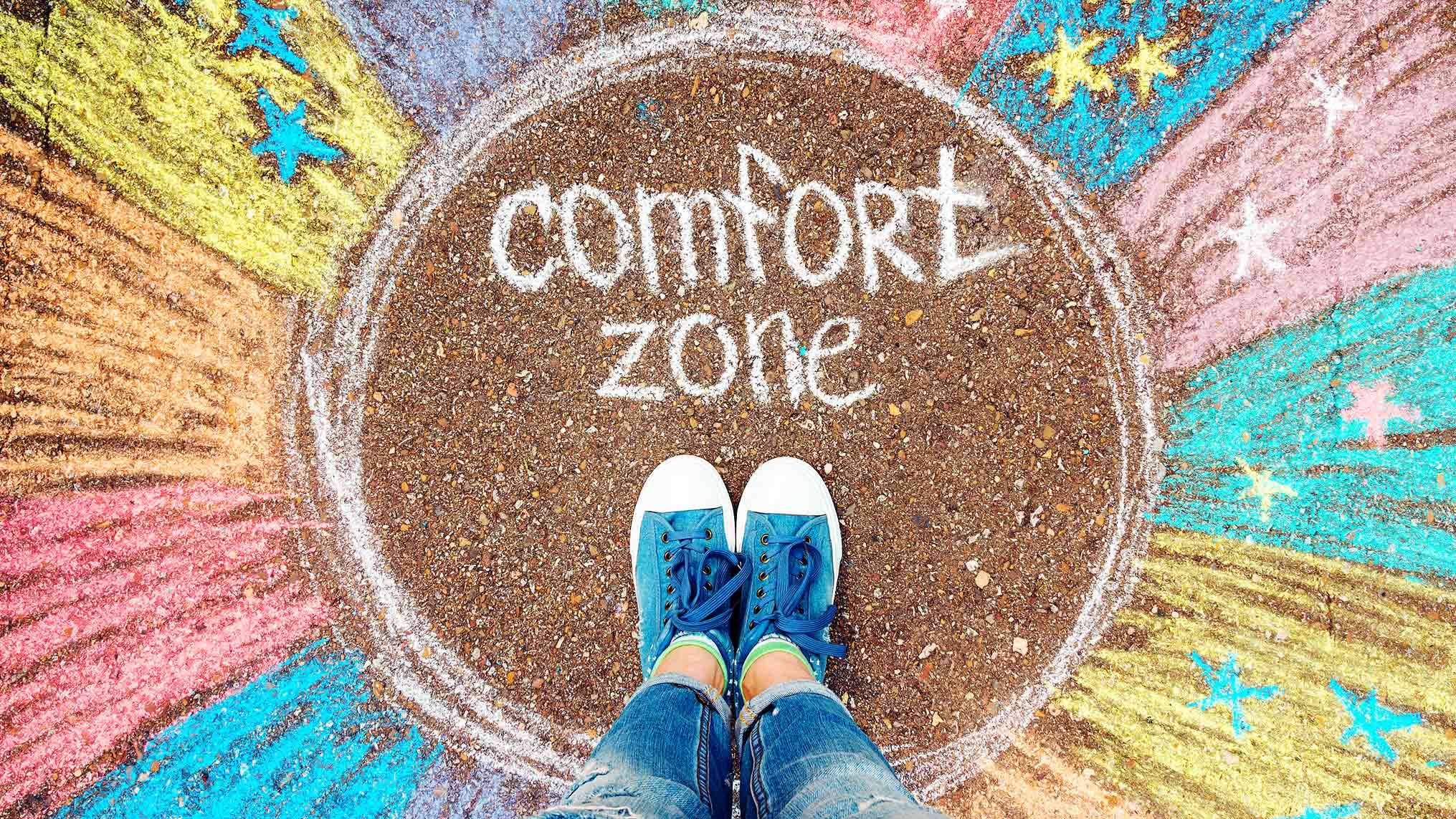 Feet standing inside a chalk-drawn comfort zone circle on the ground, representing stagnation and the limits of staying in familiar territory.