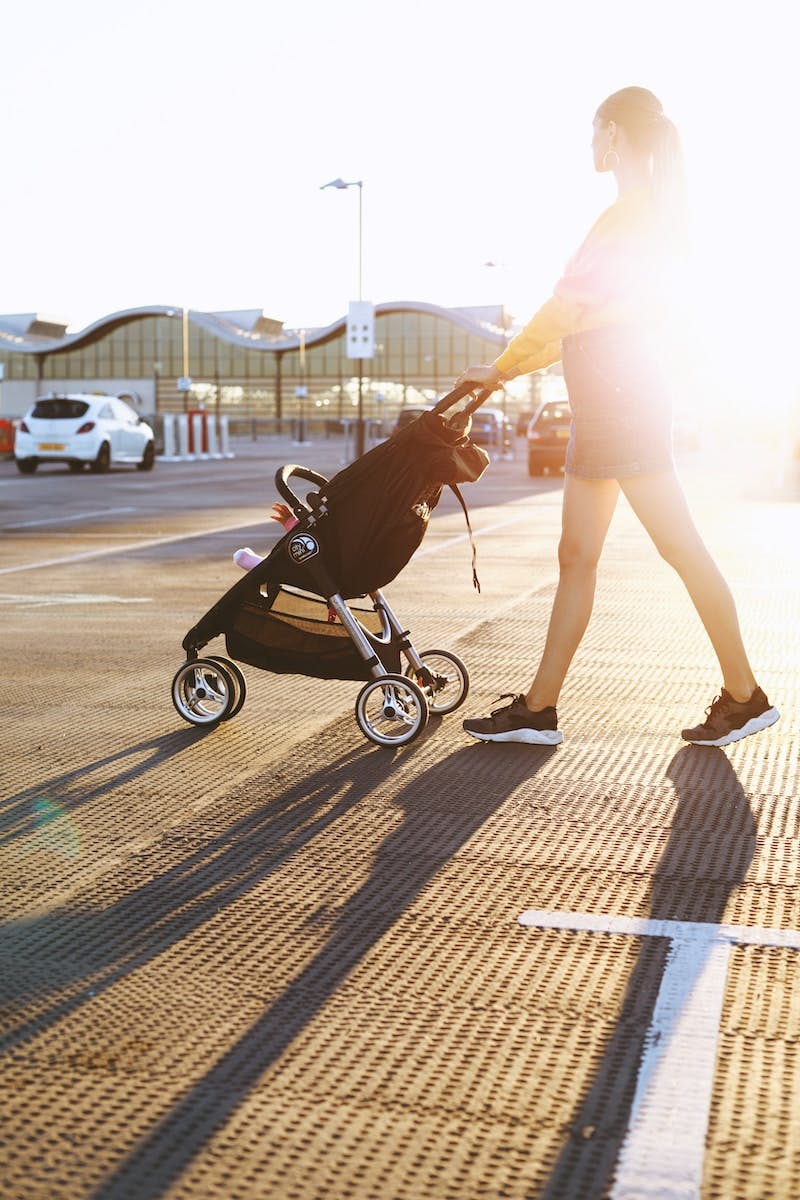woman pushing baby's stroller on parking area