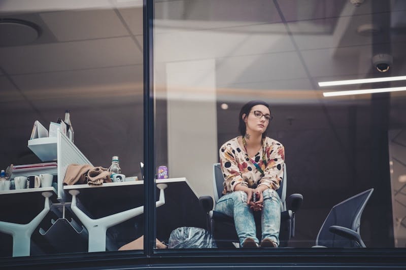 A female employee staring out of the office window, feeling insecure about her place in the world