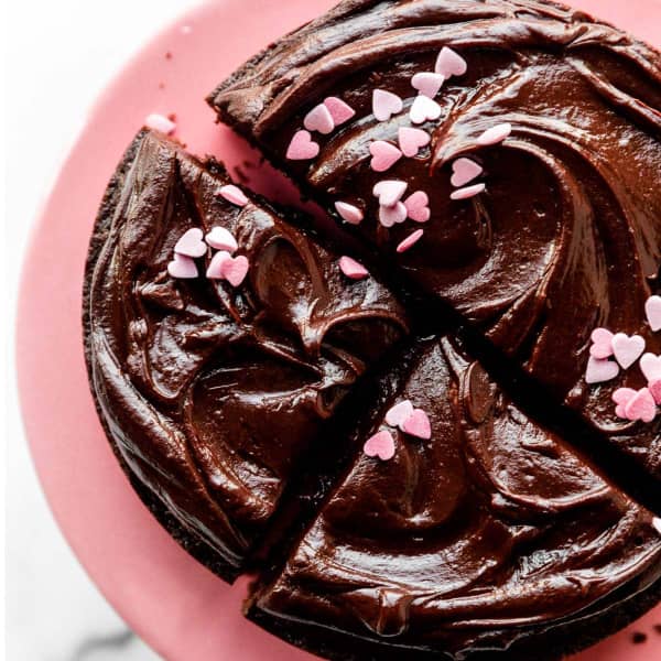 One layer chocolate cake with ganache topping on a pink cake stand