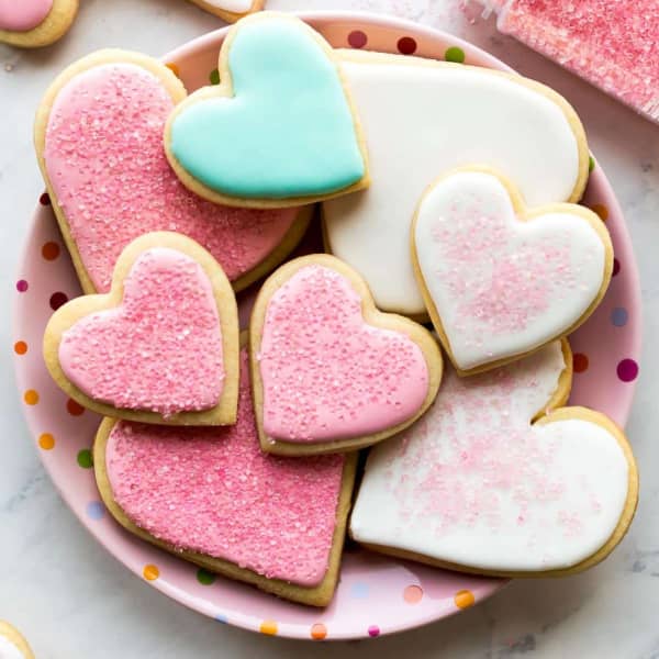 Various sized of sugar cookie hearts with pink, white, and blue icing, on a pink plate