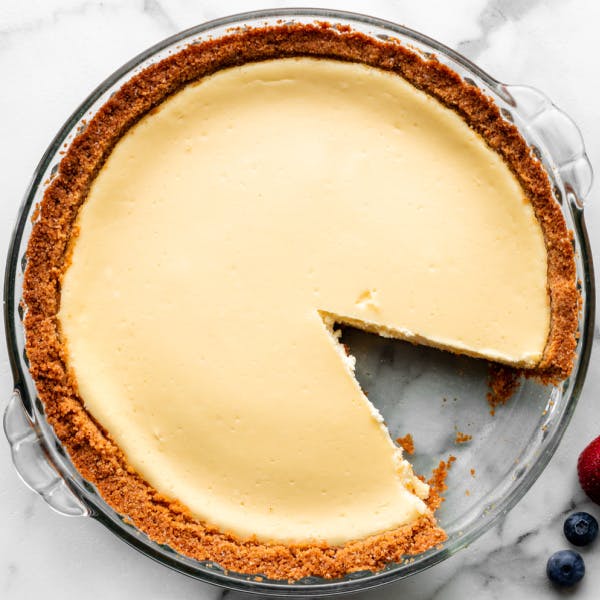 cheesecake pie with a slice removed in glass pie dish