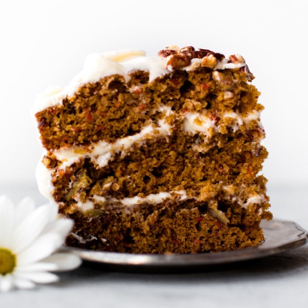 a slice of three layer carrot cake with cream cheese frosting