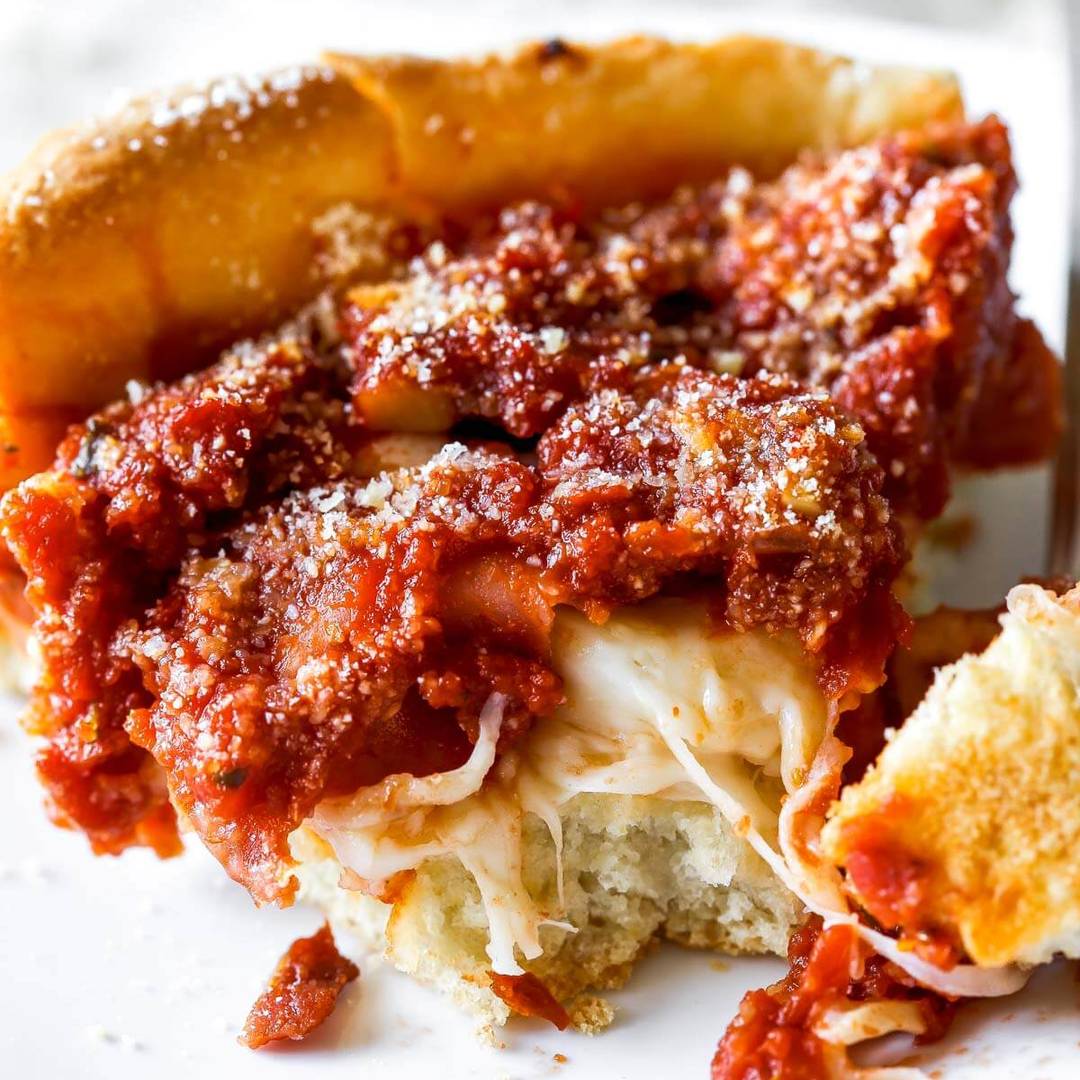 slice of deep dish pizza with a bite taken out