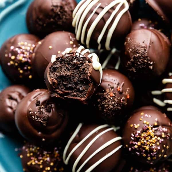 pile of Oreo balls on a blue plate, one with a bite taken out