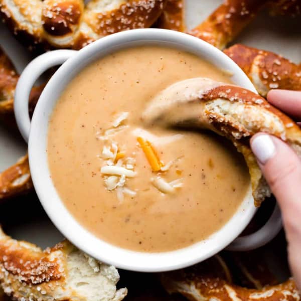 photo of soft pretzel being dipped in a creamy beer cheese dip