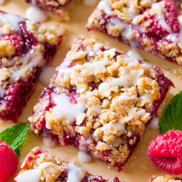 raspberry streusel bars with icing on parchment paper