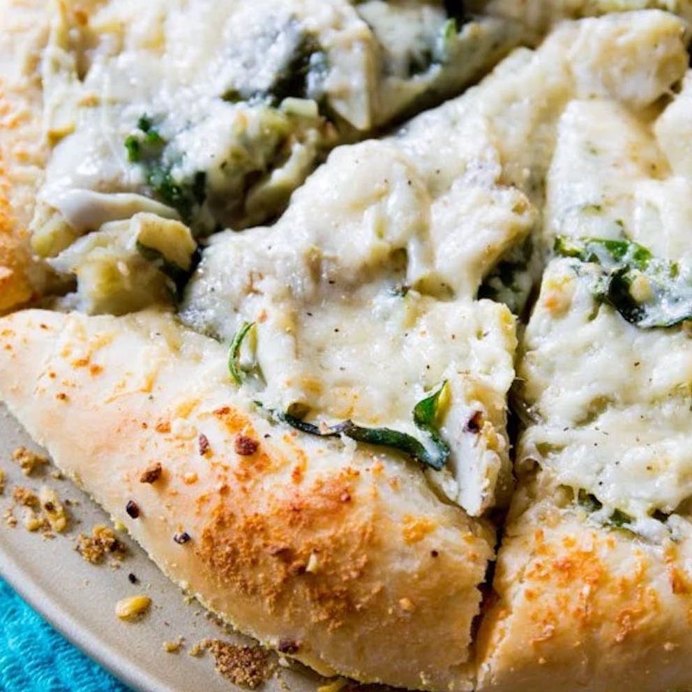 spinach artichoke white cheese pizza slices on a pizza pan
