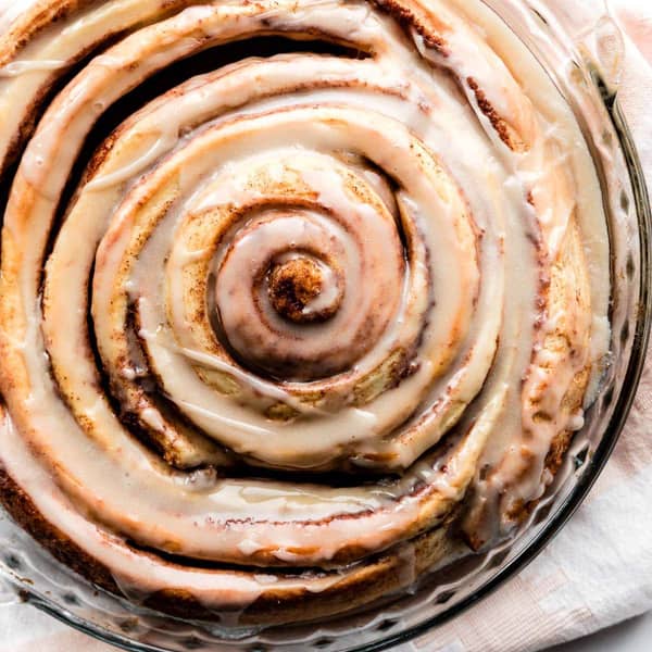 one giant cinnamon roll in a glass pie dish