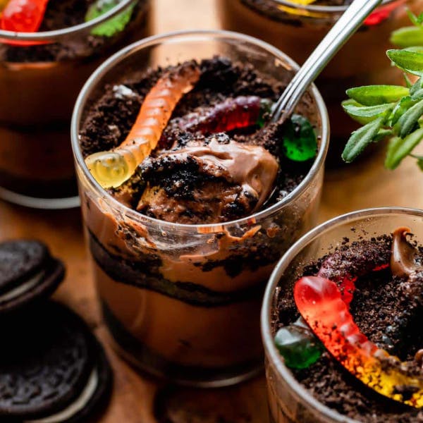 layered dirt pudding in glass cups with gummy worms