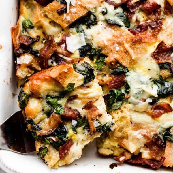 a piece of spinach & bacon strata in a casserole dish
