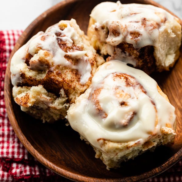 picture of three cinnamon rolls on a wooden plate
