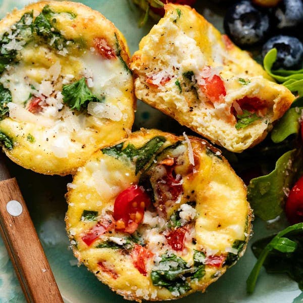 three egg muffins with tomatoes, spinach and cheese