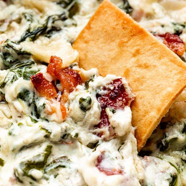 garlic bacon spinach dip with a pita chip in it