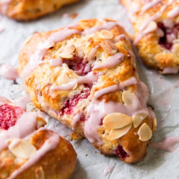 scone on parchment paper with pink icing
