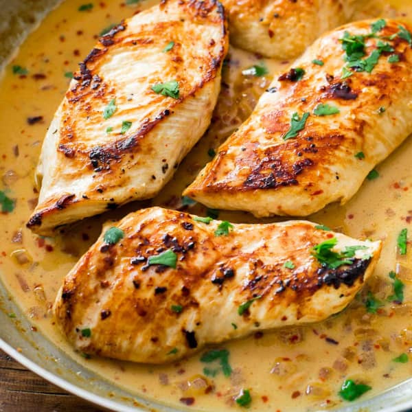 cooked chicken breasts in a pan with creamy sauce