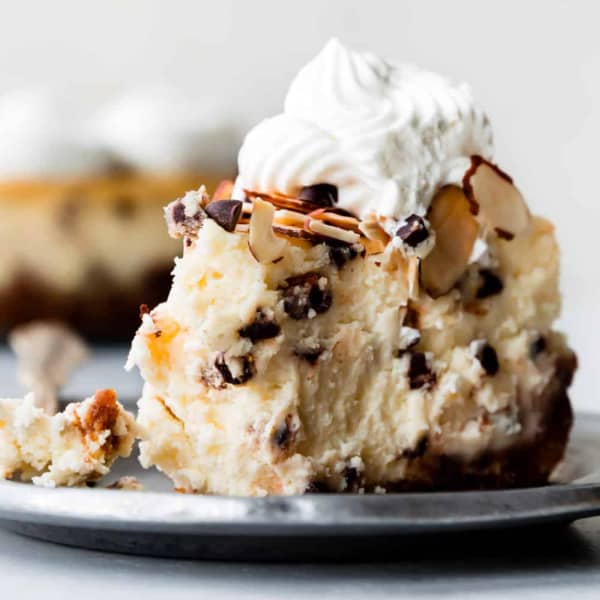 slice of amaretto cheesecake on a metal plate with whipped cream on top