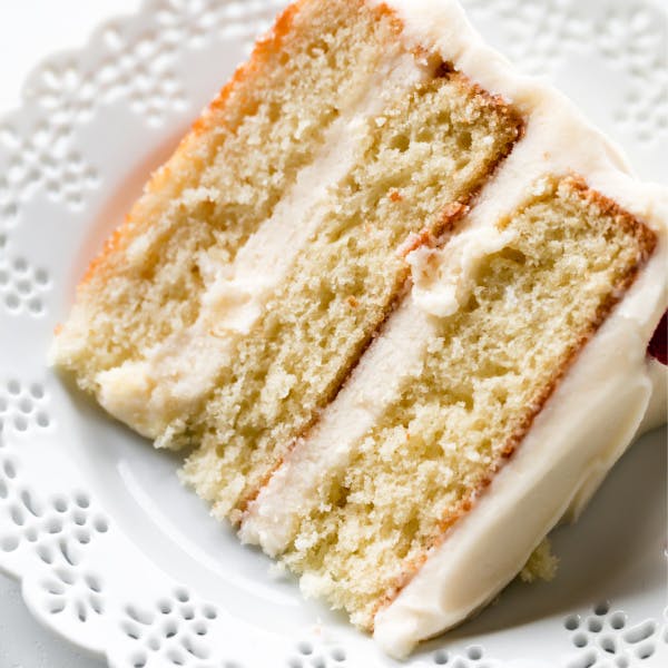 slice of three layer vanilla cake with vanilla frosting