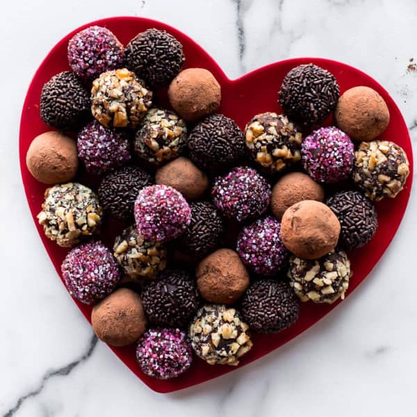 chocolate truffles with various coatings on a red heart plate