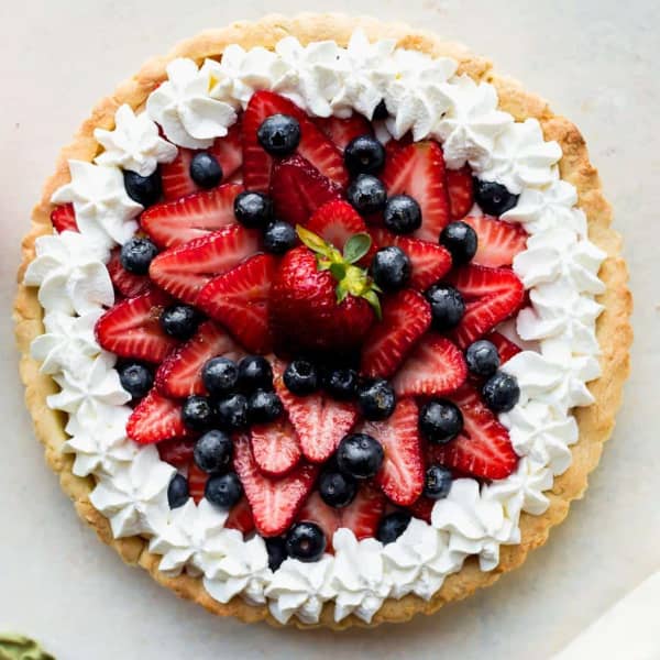 fruit tart with fresh berries and whipped cream on top