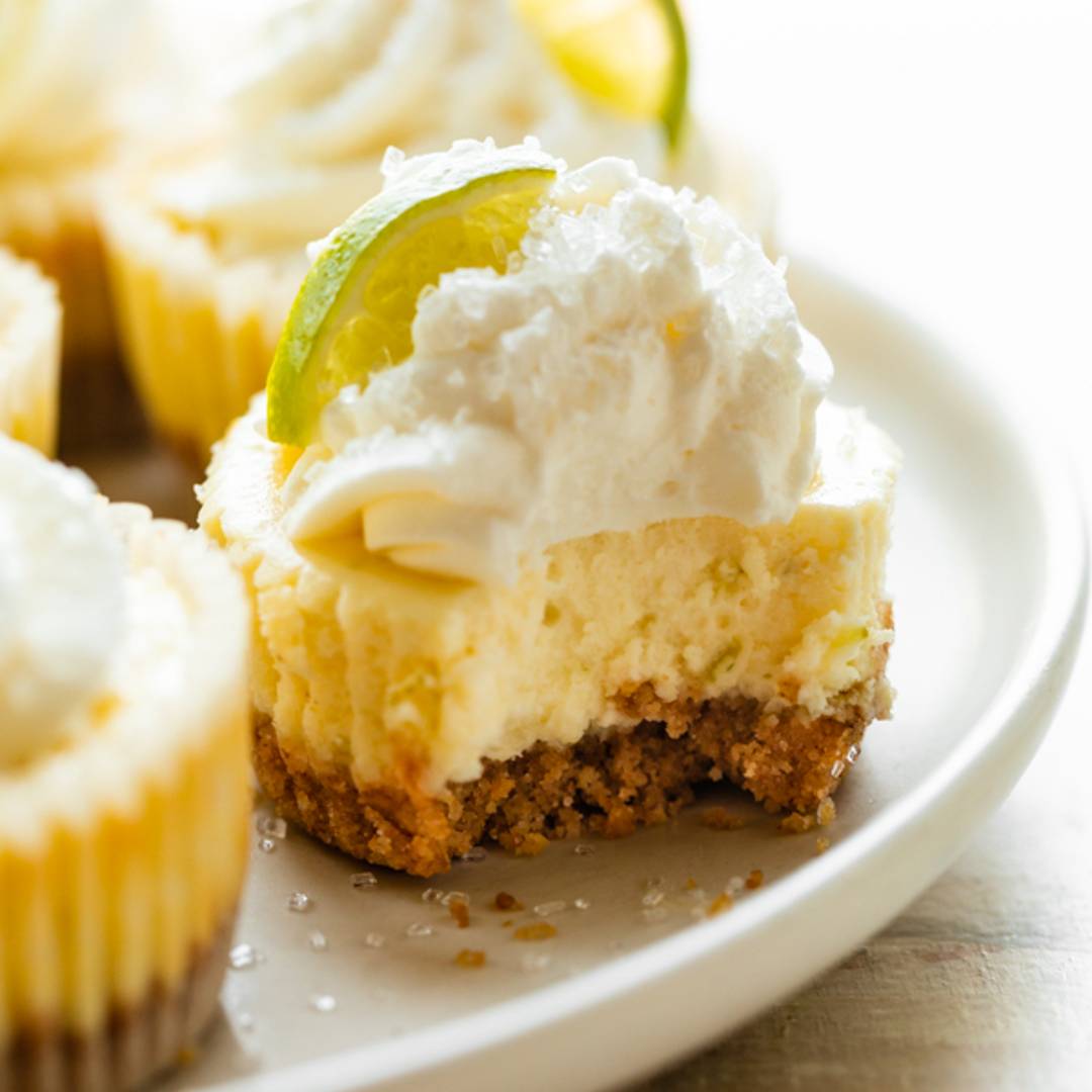 picture of a mini margarita cheesecake with whipped cream and a lime slice