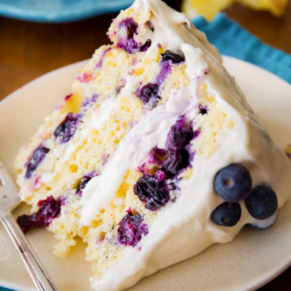slice of cake with lots of blueberries on an off-white plate