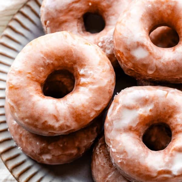 homemade glazed doughnuts stacked on a plate