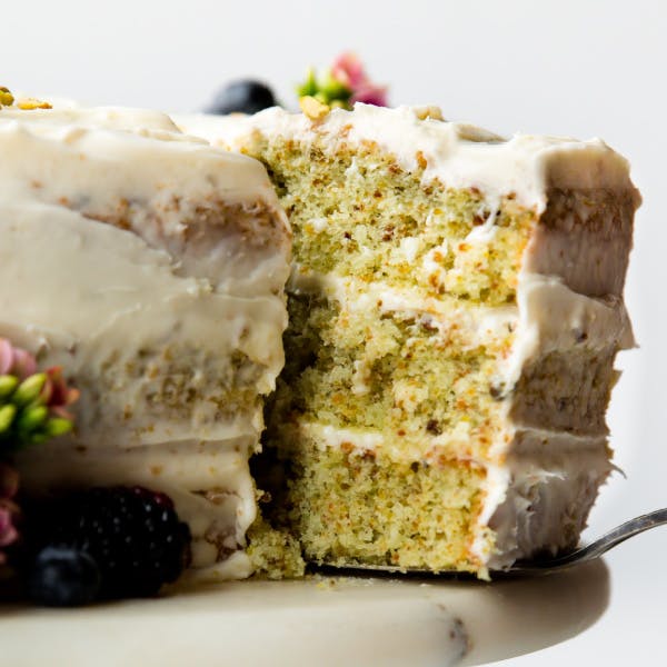 Pulling a slice of green pistachio cake from the cake stand