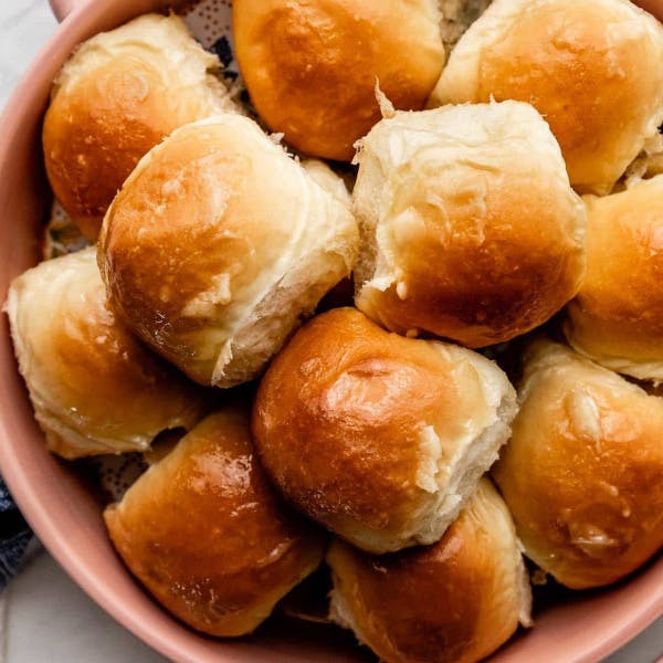 honey butter rolls stacked in a pink bowl