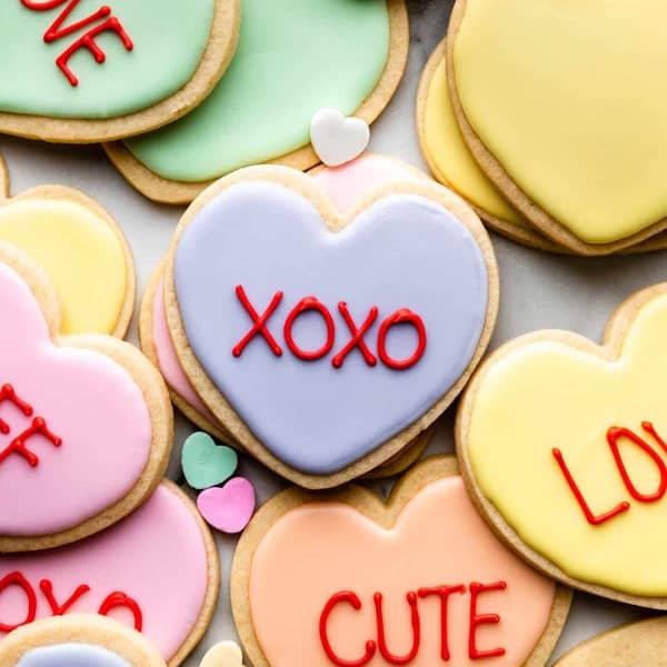sugar cookies with Patel icing and conversation heart phrases piped on top