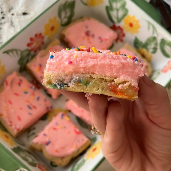 Frosted sugar cookie bars with pink icing and sprinkles