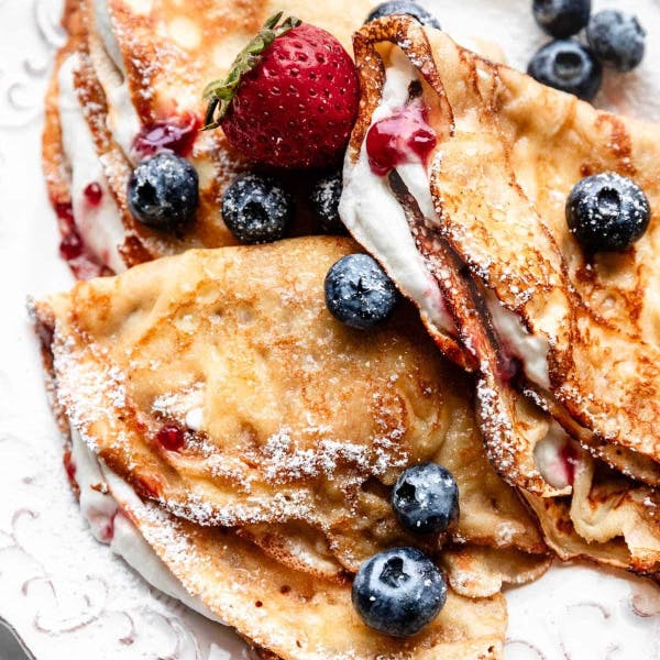 three crepes, filled with whipped cream and fresh berries