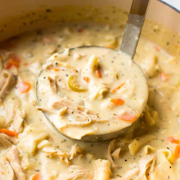 a ladle full of creamy chicken noodle soup