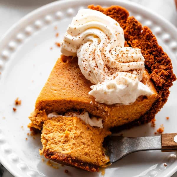 slice of pumpkin cheesecake pie with whipped cream topping