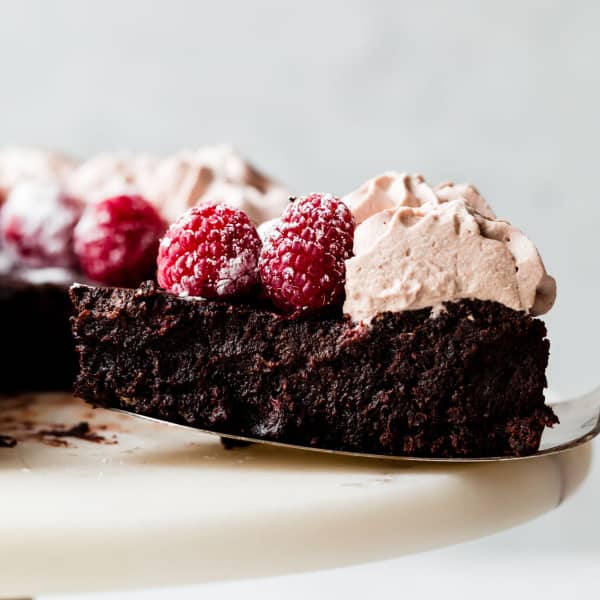 picture of a slice of flourless chocolate cake with mocha whipped cream and raspberries