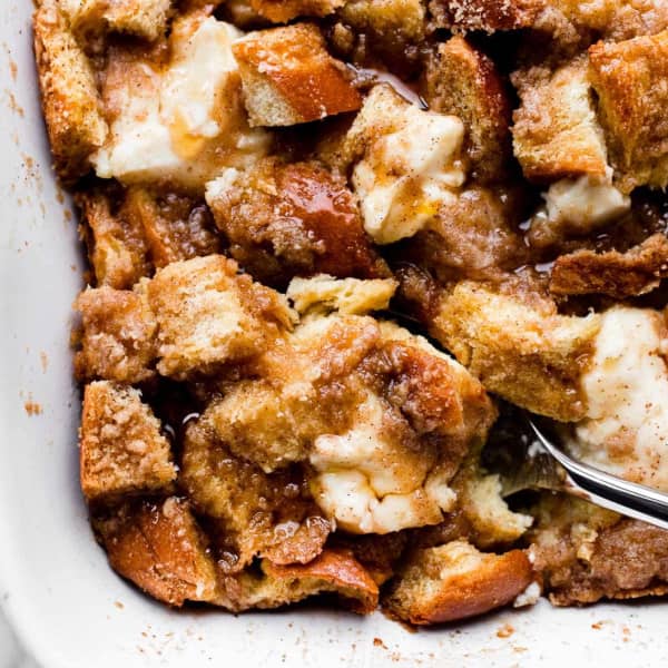 A spoon taking a scoop of golden brown casserole dotted with cream cheese