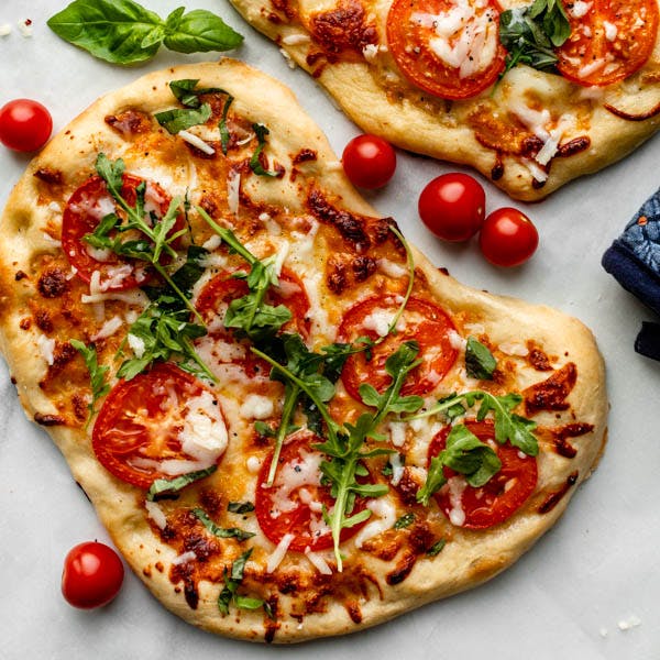 flatbread pizza with tomatoes, cheese and arugula 