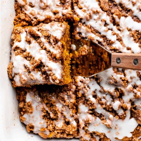 pumpkin coffee cake in a baking dish sliced into squares topped with icing