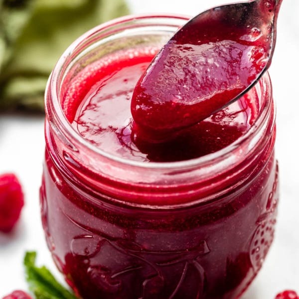 picture of a jar of raspberry sauce with spoon on top